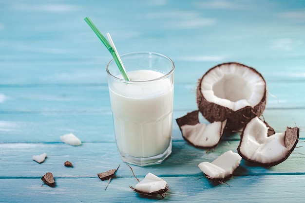 Front view of coconut milk in glass with coconut fruit on wooden table Tropical beverage