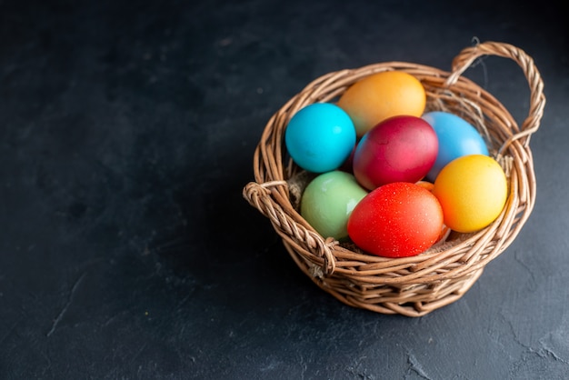 front view colored easter eggs inside basket on dark surface