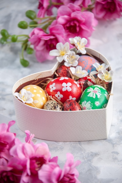 front view colored easter eggs inside heart shaped box with flowers white surface holiday concept easter spring ornate colourful