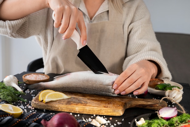 Front view cook cleaning fish in kitchen