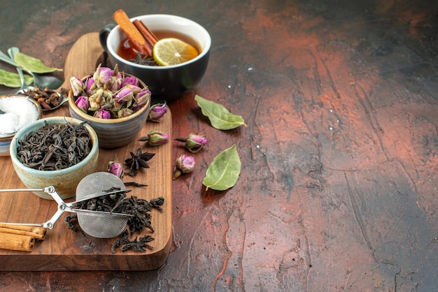 Front view cup of tea with black tea and dried flowers on dark brown background tea fruit water color breakfast photo drink ceremony free space