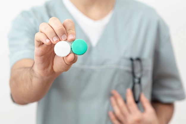 Front view of defocused eye specialist holding contact lenses case