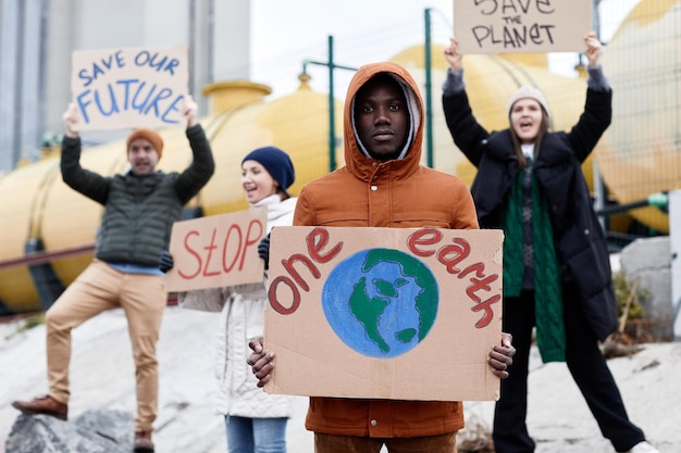 Front view at diverse group of people holding signs holding and shouting while protesting at environ...