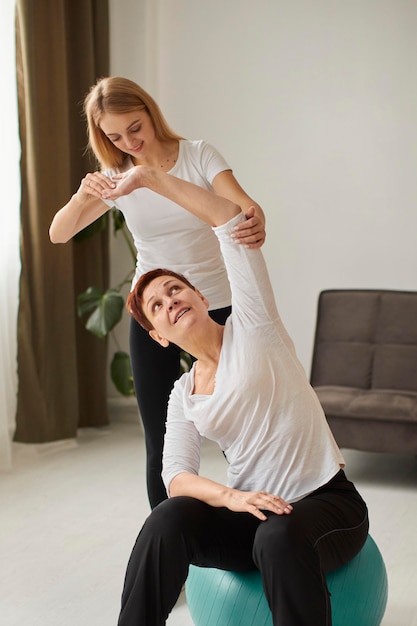 Front view of elder woman in covid recovery doing exercises with nurse