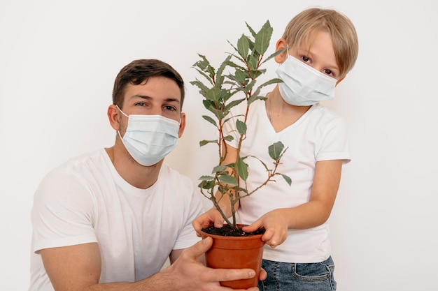 Front view of father and son holding pot of plant