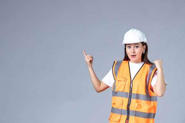 Front view of female builder in uniform on gray wall