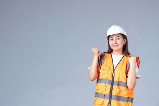 Front view of female builder in uniform on white wall