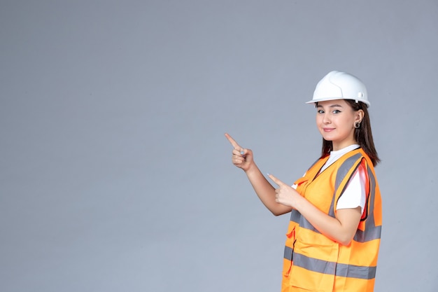 Front view of female builder in uniform on white wall