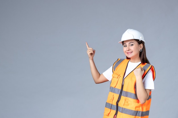 Front view of female builder in uniform on white wall