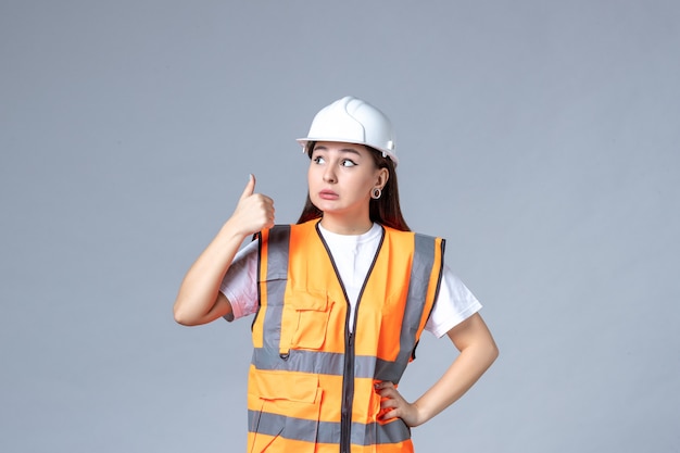 Front view of female builder in uniform on white wall