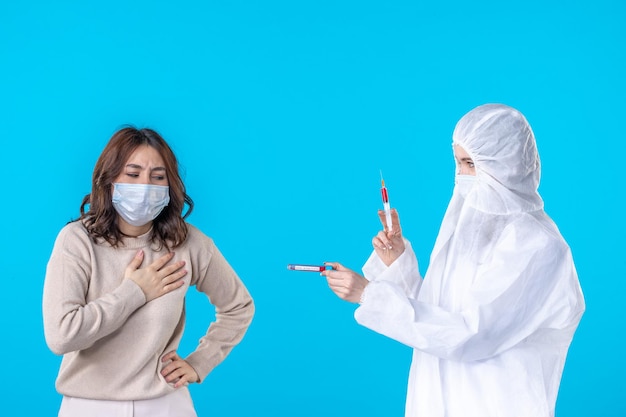 front view female doctor in protective suit with ill patient on blue background medical virus covid pandemic disease science health