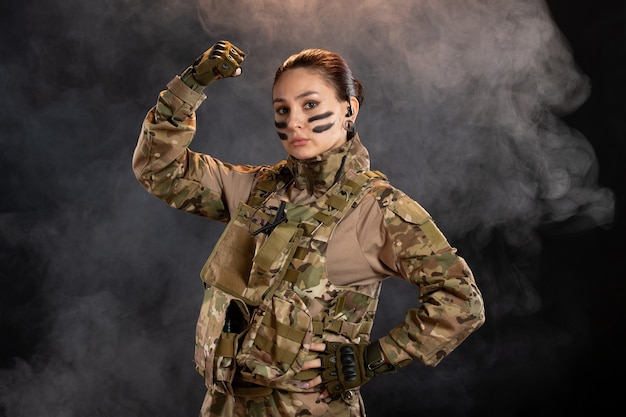 Front view of female soldier in camouflage black smoky wall