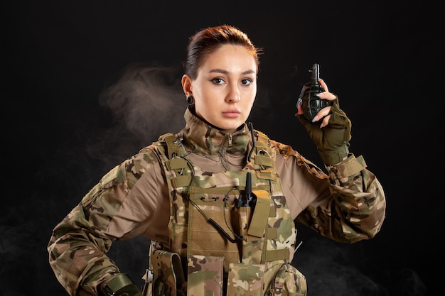 Front view of female soldier with grenade in uniform black wall