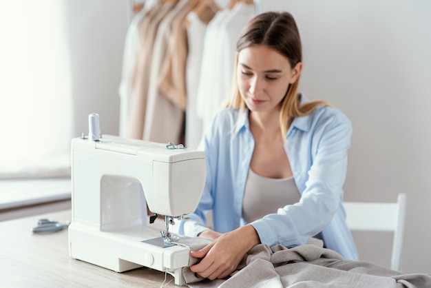 Front view of female tailor using sewing machine in the studio