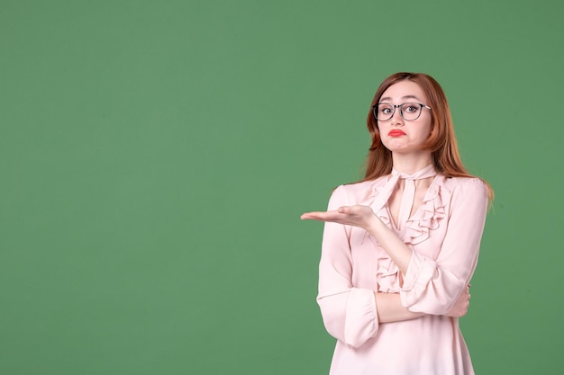 Front view female teacher in pink blouse on green background school color library college work job woman young book lesson