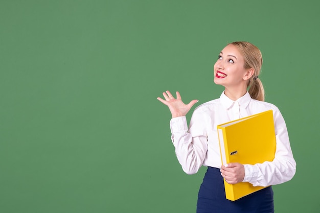 Front view female teacher posing with yellow files on green background book school woman library study university uniform work students lesson