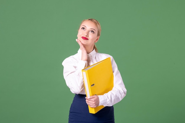 Front view female teacher in strict clothes with yellow files on green