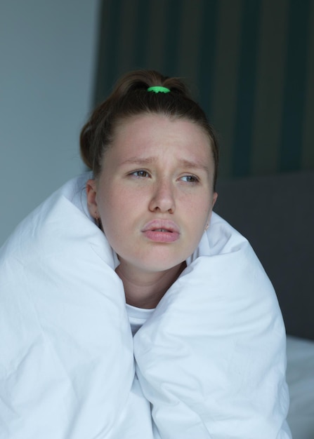 Front view of a frustrated upset young frozen woman wrapped staring into the distance with soft