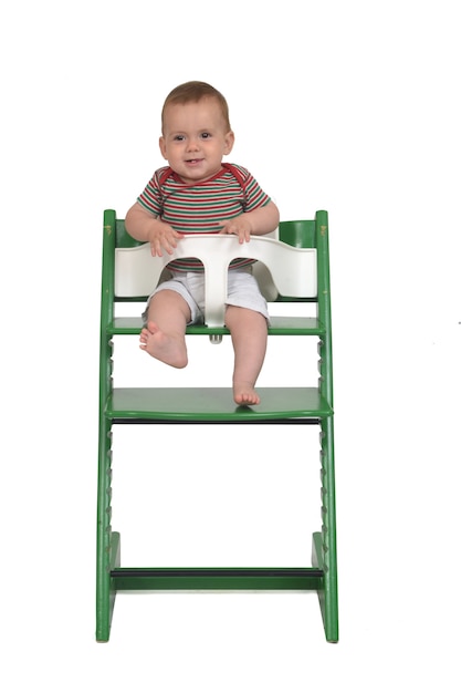 Front view of a full portrait of a baby sitting in a highchair laughing on white background