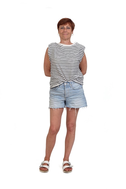 Front view of a full portrait of a middle aged woman looking at camera and arms on back on white background