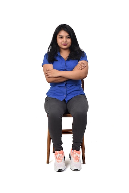 Front view of full portrait of a woman dressed in jeans sneakers and shirt arms crossed and looking at camera on white background