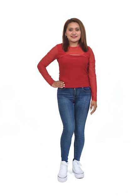 Front view of a full portrait of a women with jeans and sneaker looking at camera and hand on hip over white background