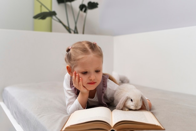 Front view girl reading with bunny