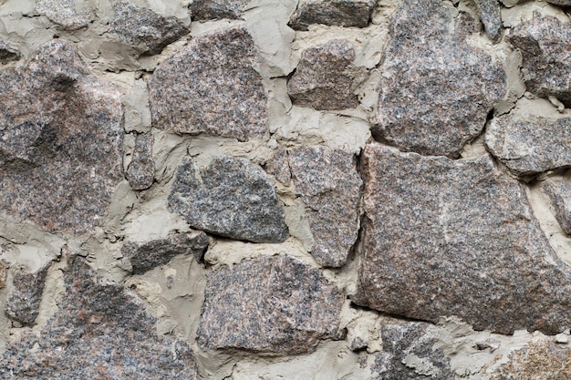 Front view of gray stone wall with cement solution. Natural stone texture.