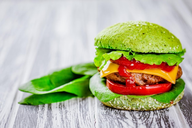 Front view of green homemade burger with marble beef with veggies greenery on wooden table