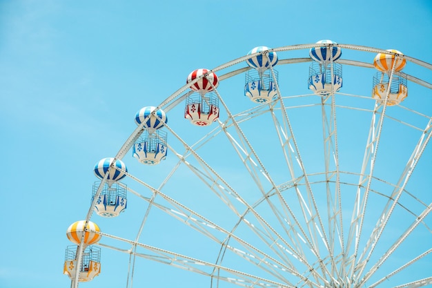 Front view of half retro colorful Ferris wheel at amusement park over blue sky background