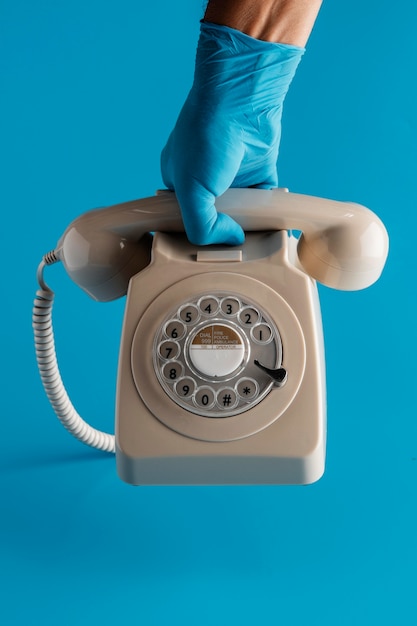 Front view of hand with glove holding telephone with receiver