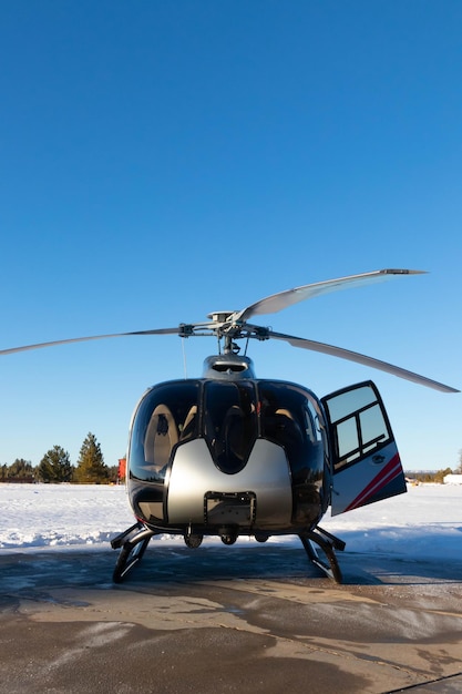 Front view of helicopter surrounded by snow with blue sky