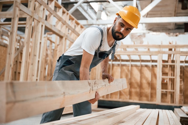 Front view holding plank Industrial worker in wooden warehouse