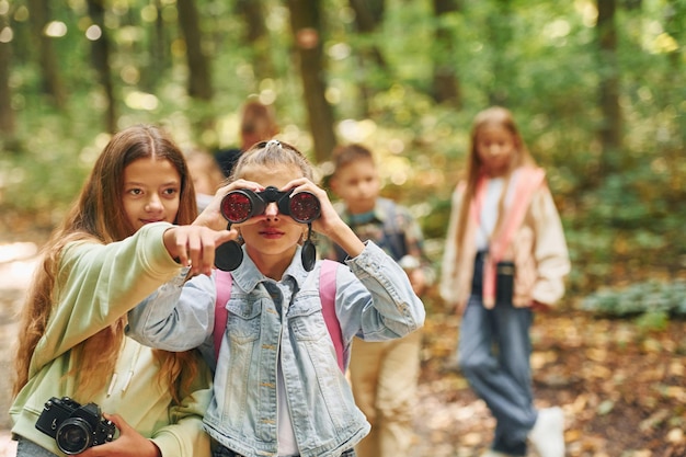 Photo front view of kids that is in green forest at summer daytime together