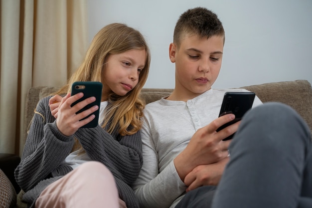 Front view kids with devices on couch