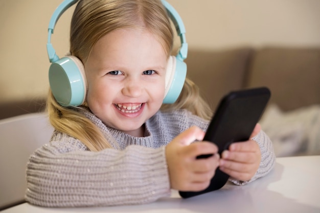 Front view of little girl with headphones and phone