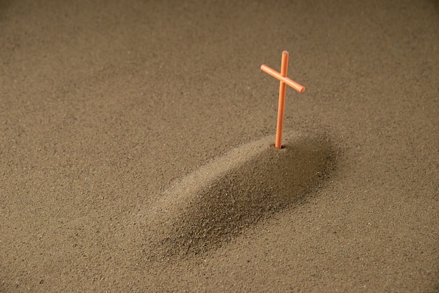 Front view of little grave with cross on dark