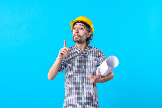 Front view male builder holding plan on a blue background architecture constructor engineer job building color skyscraper