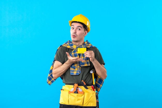 front view male builder in yellow helmet holding bank card on blue background money color flat architecture building workers constructor