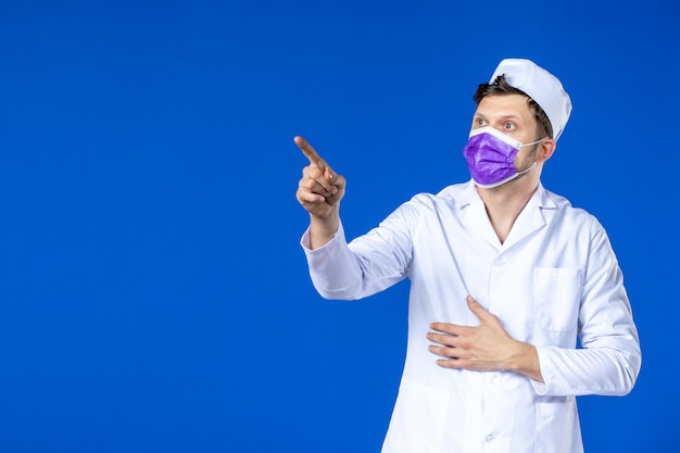 Front view of male doctor in medical suit and purple mask on blue 