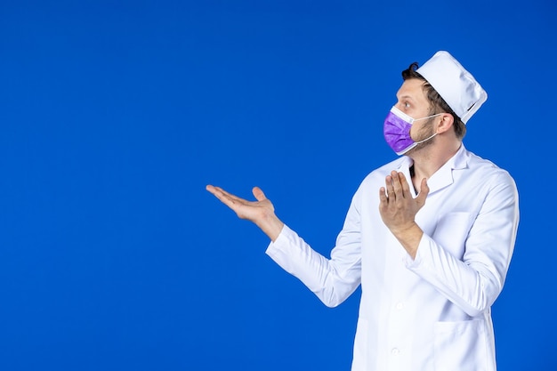 Front view of male doctor in medical suit and purple mask on blue 