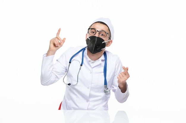 Front view male doctor in medical suit wearing special black mask