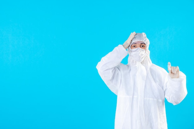 Front view male doctor in protective suit and mask on blue