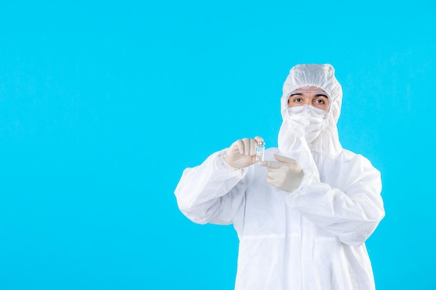 Front view male doctor in protective suit and mask on blue