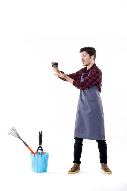 front view male gardener holding black bank card on a white background work garden job ground uniform money soil flower