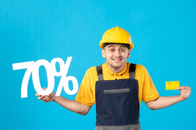 Front view of male worker in uniform with writing and credit card on blue 