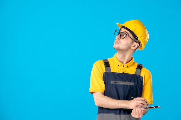 Front view of male worker in yellow uniform taking notes on blue 