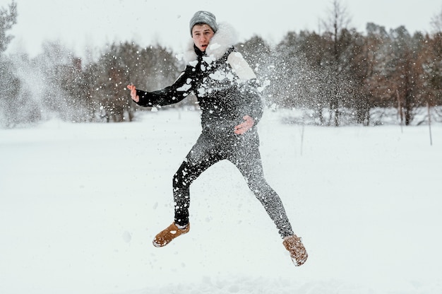 Front view of man jumping outdoors in winter