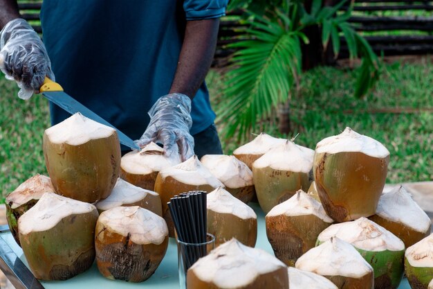 Photo front view of a man preparing coconut fruits with a knife