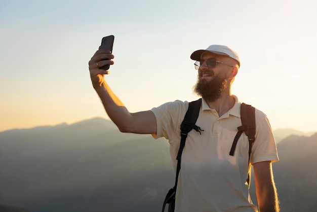 Front view man taking selfie on mountain